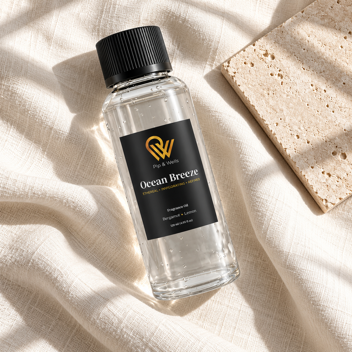 Butelka olejku zapachowego Pip & Wells Ocean Breeze o pojemności 120 ml na jasnym lnie obok płytki kamiennej z fakturą
