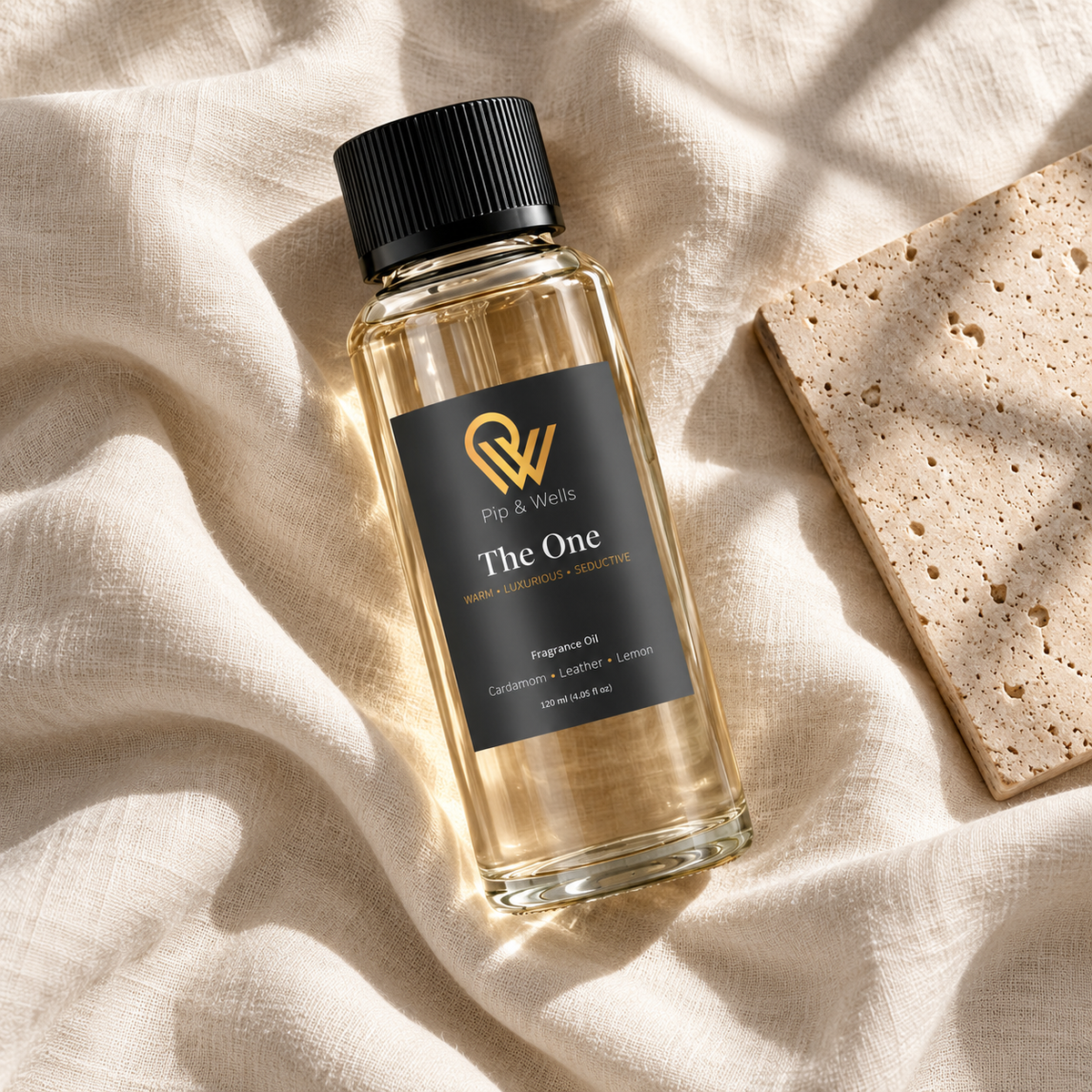 Butelka olejku zapachowego Pip & Wells The One o pojemności 120 ml na jasnym lnie obok płytki kamiennej z fakturą